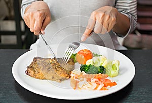 Girl eating pork steak with knife and fork