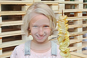 Girl eating potato chips on a stick. Junk food, street food, snack on a walk.