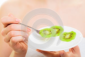 Girl eating slices of kiwi fruit. Healthy diet.