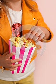 The girl is eating sweet popcorn. Hands and a bowl of popcorn close-up