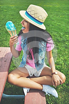 Girl, eating and tongue out by ice cream at park sitting with vanilla or bubblegum flavor for summer. Woman, lick and