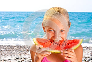 Girl eating watermelon on seashore or beach