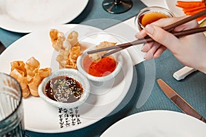 Girl eats Chinese food from a plate with chopsticks. Close-up of hands and food. Lifestile.