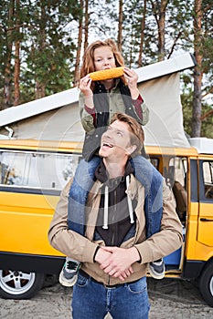 Girl eats corn while sitting on dad`s shoulders