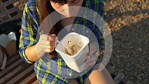 Girl eats hot noodles on pebble beach