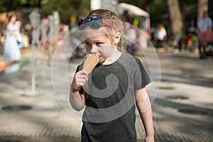The girl eats ice cream on the street.