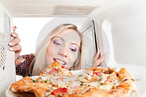 Girl eats pizza out of the microwave