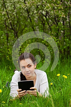 Girl with ebook lying on the grass