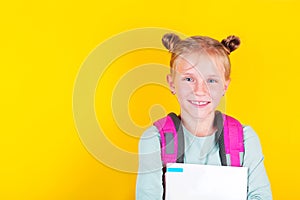 Girl from elementary school with book and backpack on yellow background. School concept, education. Back to School