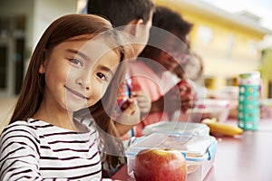 Girl at elementary school lunch table smiling to camera