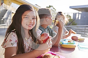 Girl at elementary school lunch table smiling to camera