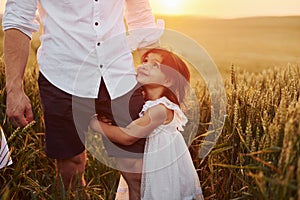 Girl embraces parent. Father with daughter spending free time on the field at sunny day time of summer