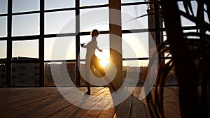 The girl is engaged in modern jazz ballet in a loft studio. A woman is spinning in a sunny room