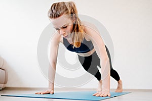 Girl is engaged in sports at home online workouts on laptop. pushups and plank