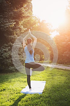 Girl is engaged in yoga in the park, doing exercises. Training on the street in the summer morning. Concept sport healthy