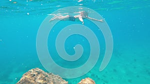 Girl engaging snorkeling swimming under the water. Woman in a swimming suit freediving at the depth of the sea.