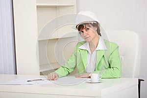 Girl engineer in white helmet on workplace
