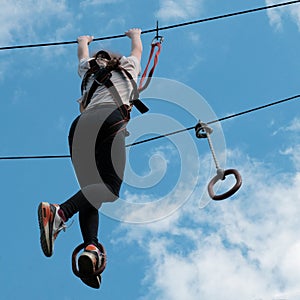 A girl enjoying climbing at adventure park. Zip line activity. Square picture.