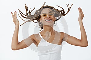 Girl enjoying cool new hairstyle being ready to party rock. Portrait of joyful carefree stylish dark-skinned woman with