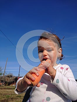 Girl enjoying her carrot on a sunny day