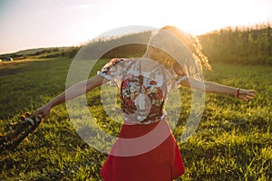 Girl enjoying nature on the field . The girl is joyful spinning with a wreath of flowers in her hands