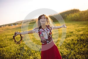 Girl enjoying nature on the field . The girl is joyful spinning with a wreath of flowers in her hands