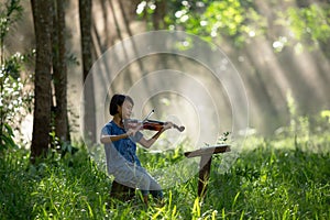 Girl is enjoying playing violin or playing his music in the wild