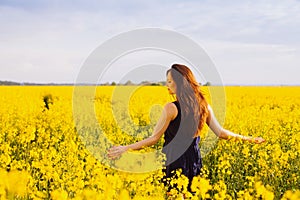 Girl enjoying rapeseed blooming on yellow meadow