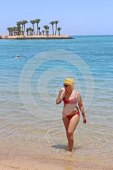 Girl enjoying relax drinking coffee on beach. Woman relaxing standing in sea