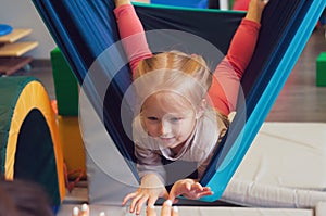 Girl enjoying a sensory therapy on a hammock while physiotherapist assisting her