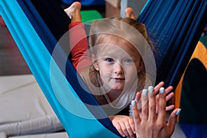 Girl enjoying a sensory therapy on a hammock while physiotherapist assisting her