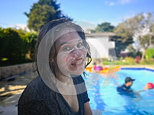 Girl enjoying summer vacation in the pool. Smiling face covered in sunscreen