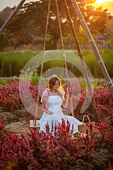 Girl enjoying the sunset on a swing in a flower-filled meadow