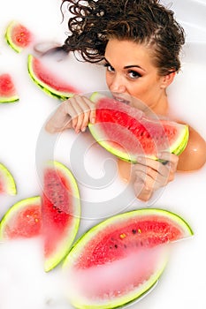 Girl enjoys a bath with milk and watermelon.