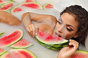 Girl enjoys a bath with milk and watermelon. photo