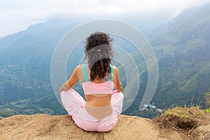 Girl enjoys a mountain view while standing on a cliff