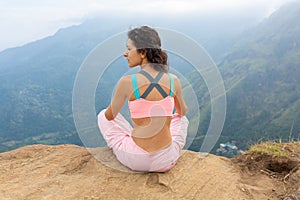 Girl enjoys a mountain view while standing on a cliff