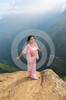 Girl enjoys a mountain view while standing on a cliff