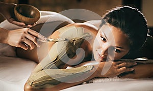 The girl enjoys mud body mask in a spa salon. Focus on the hand with the stick