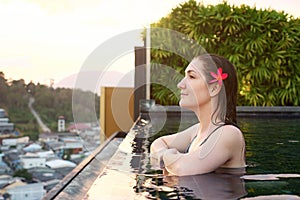 Girl enjoys pictorial landscape standing in outdoor swimming pool in summer