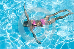 Girl enjoys an underwater swim in pool