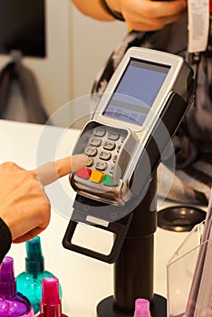 The girl enters the pin code on the terminal to pay for purchases in store