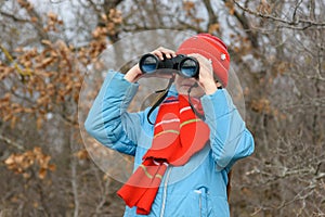 Girl enthusiastically looks through binoculars, front view, close-up