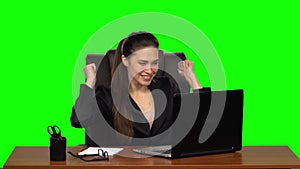 Girl enthusiastically works behind a laptop, smiles and enjoys the result. Green screen. Slow motion