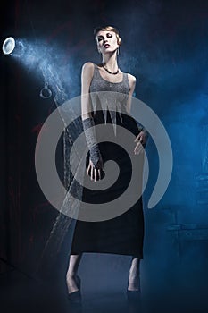 The girl in a evening dress in fog in a bdsm interior