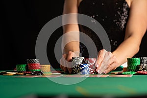 A girl in an evening dress plays poker by raising bets with chips in a casino. focus on chips in focus