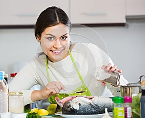 Girl eviscerating salmon fish in domestic kitchen