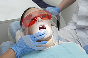 Girl on examination at dentist. treatment of carious tooth. the doctor uses a mirror on the handle and a boron machine