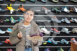 Girl examine compare item of winter comfortable tracking shoes