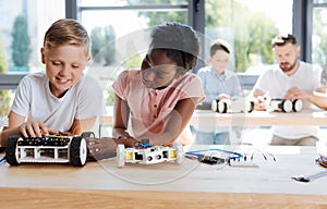 Girl examining the wheel of her friends robotic vehicle